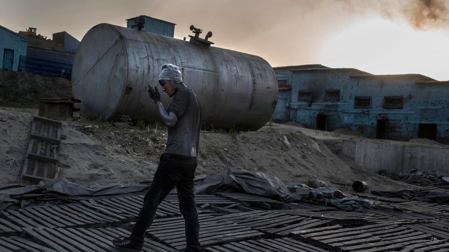 中国马山 — 5 月 28 日，一名石墨工人走过晋江