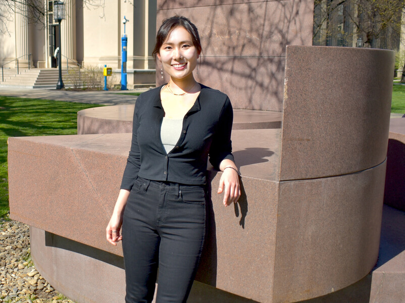 Jeong Min Park poses leaning on an outdoor sculpture in Killian Court.